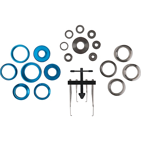 Anordnung verschiedener Metallteile: Blaue, silberne und graue Ringe, Werkzeug auf weißem Hintergrund.